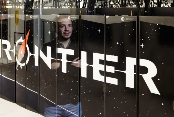 photo of front of Frontier supercomputer with researcher shown in the reflection.