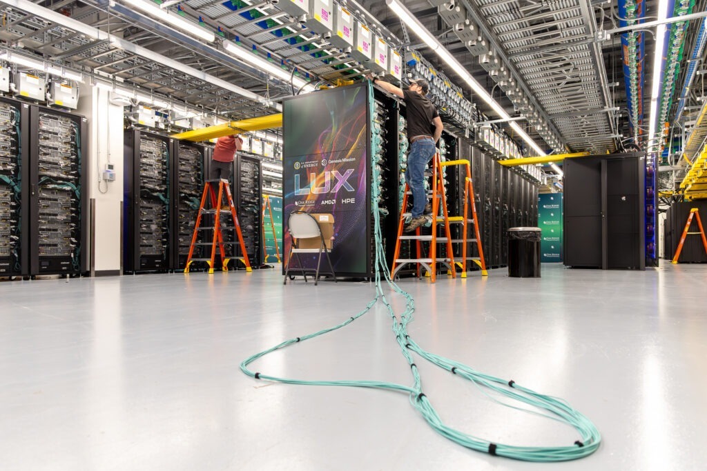 26_P000102 Technicians install and connect LUX supercomputer cabinets inside the Oak Ridge Leadership Computing Facility while engineers inspect equipment and route networking infrastructure during system integration at Oak Ridge National Laboratory.
