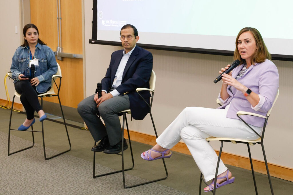 Three panelists sit onstage with microphones during a fireside chat at the Oak Ridge Leadership Computing Facility User Summit.