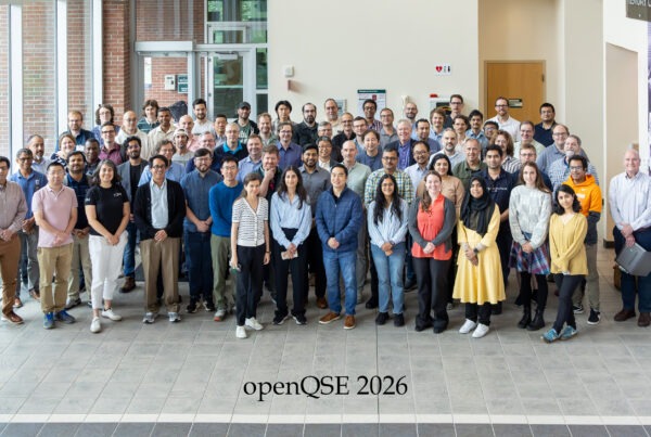 A group of people standing in a hallway behind the words OpenQSE 2026