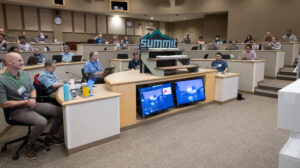 People in a room with computers and a display of cupcakes with a sign that says Summit